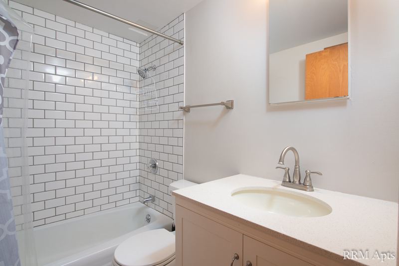 Bathroom with white subway tile shower, vanity and toilet, Slusser Street apartment 3