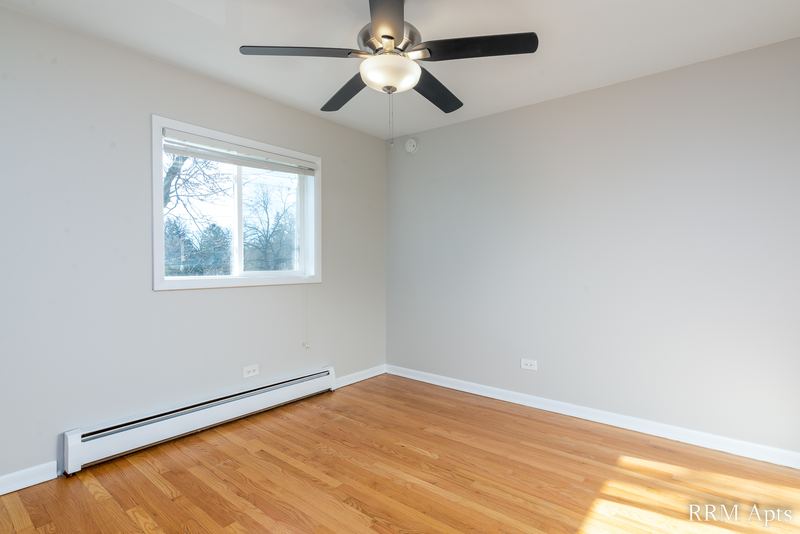 Empty room with wood floor, ceiling fan, one window and a baseboard heater, Slusser Street apartment 6
