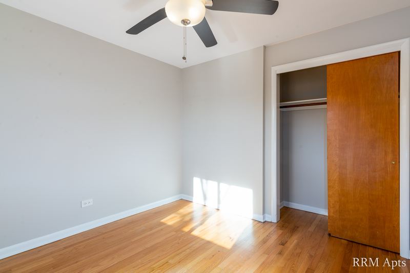 Bedroom with wood floor, ceiling fan, sunlight and an open closet with wood sliding door, Slusser Street apartment 6