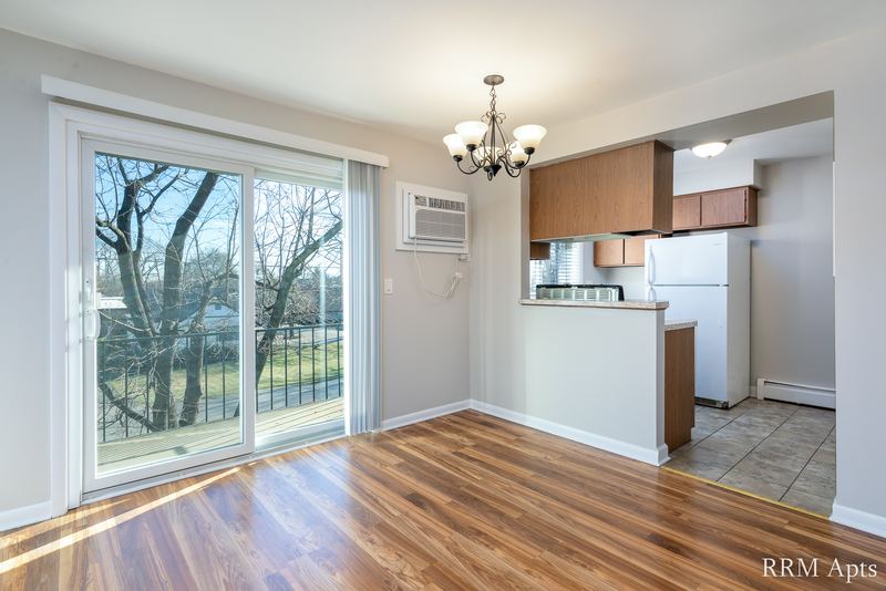 Dining area with wood floor, sliding glass door, chandelier and open kitchen with oak cabinets, Slusser Street apartment 6