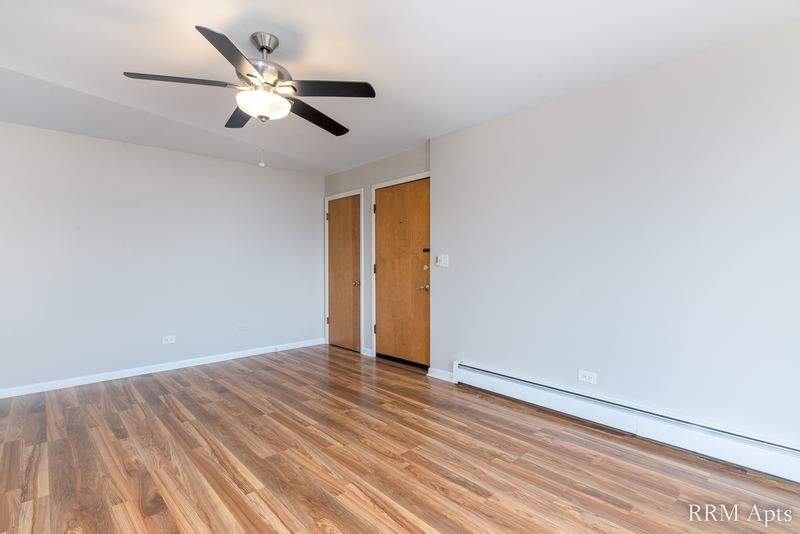 Living room with wood floor, ceiling fan, two wood doors and baseboard heater, Slusser Street apartment 6