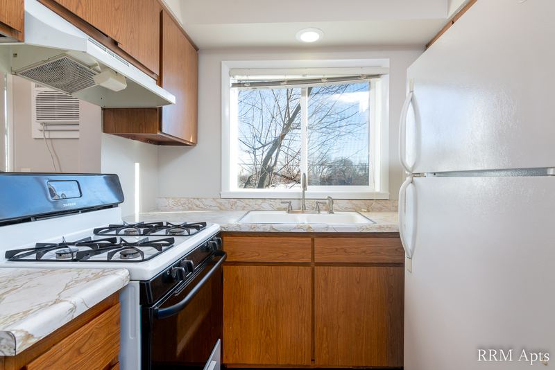 Kitchen with oak cabinets, black gas stove, white refrigerator and window over the sink, Slusser Street apartment 6
