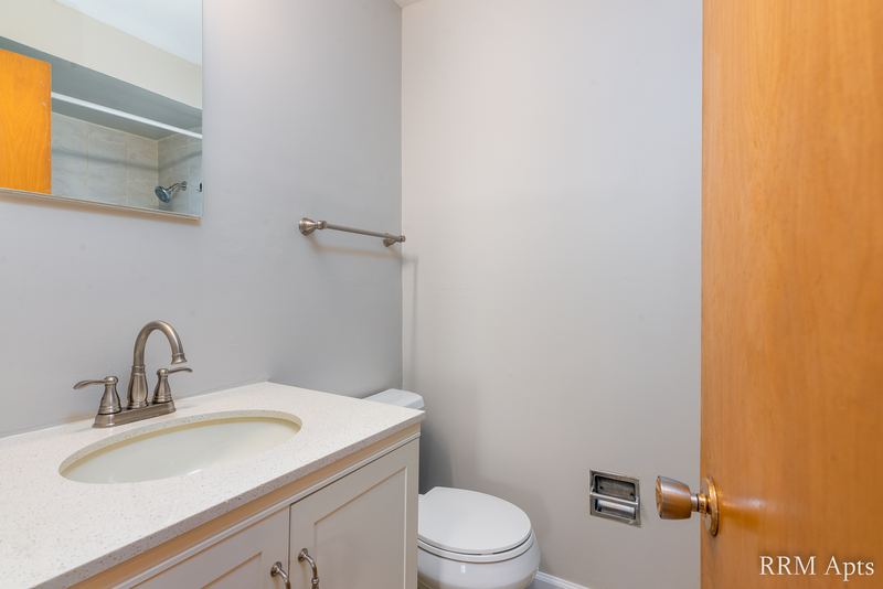 Bathroom with vanity, white counter, mirrored cabinet, toilet and wood door, Slusser Street apartment 6