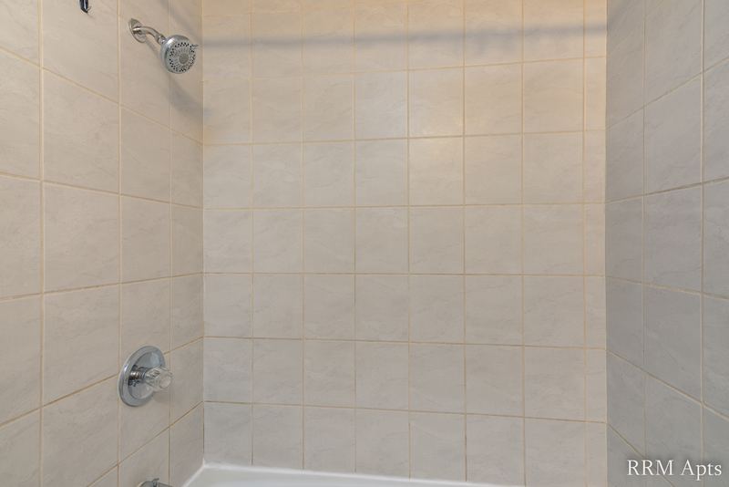 Bathroom with beige tile tub surround and shower head, Slusser Street apartment 6