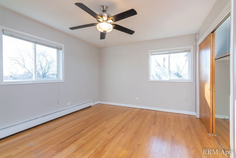 Bedroom with wood floor, ceiling fan, two windows and a wood sliding closet door, Slusser Street apartment 6