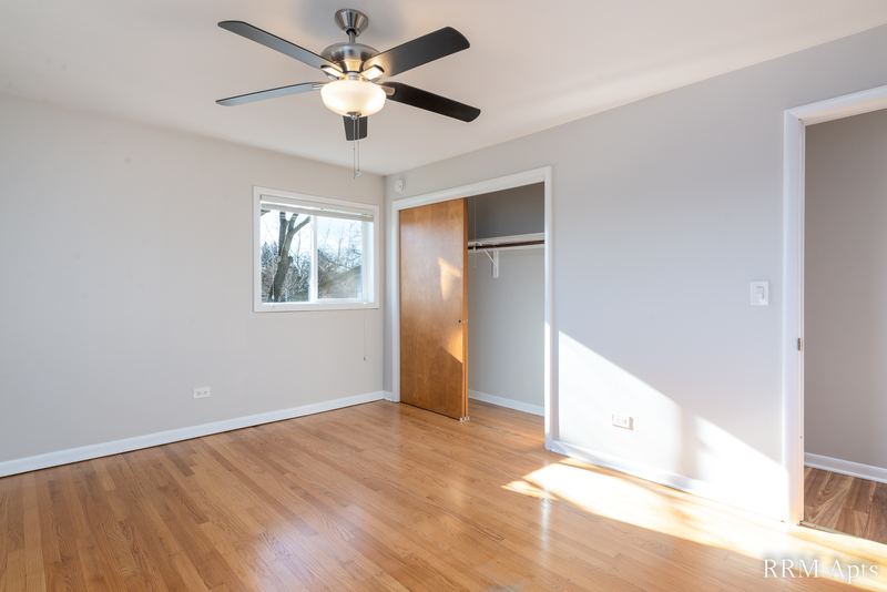 Bedroom with wood floor, ceiling fan, window, open wood-door closet and a doorway, Slusser Street apartment 6