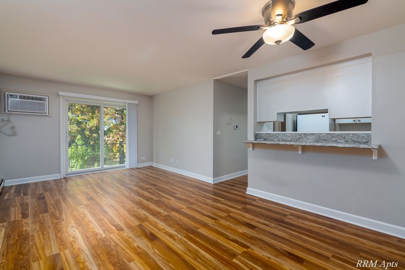 Living room with wood floor, ceiling fan, wall air conditioner and kitchen pass-through, Slusser Street apartment 7