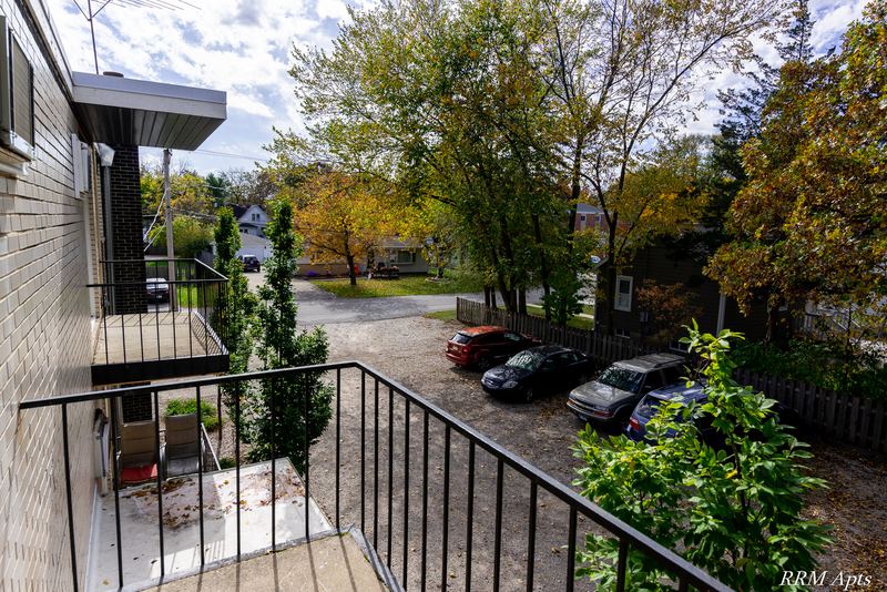 Balcony with black metal railing overlooking the parking lot and trees, Slusser Street apartment 7