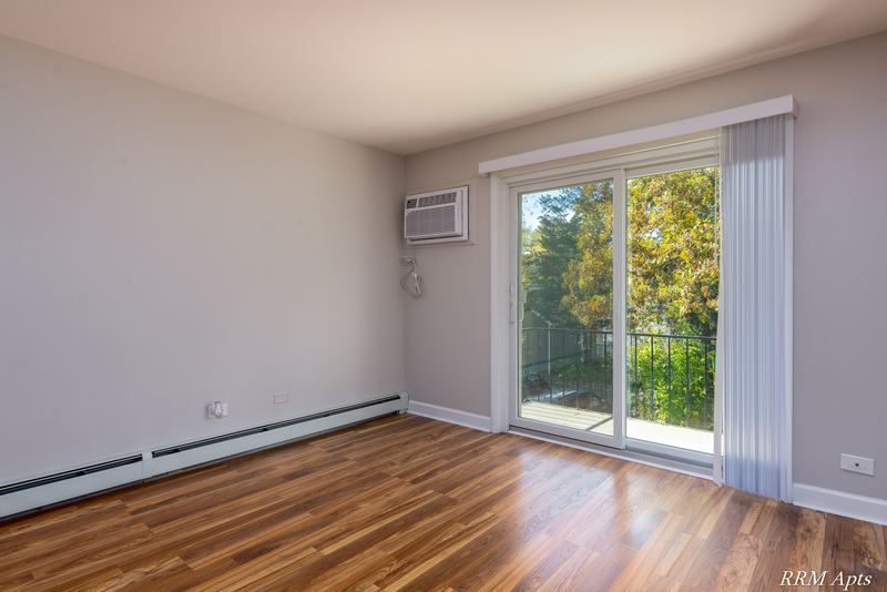 Living room with wood floor, wall air conditioner, sliding glass door and vertical blinds, Slusser Street apartment 7