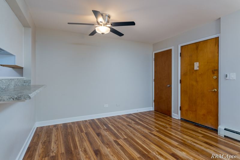 Dining area with wood floor, ceiling fan, wood entry door and kitchen pass-through counter, Slusser Street apartment 7