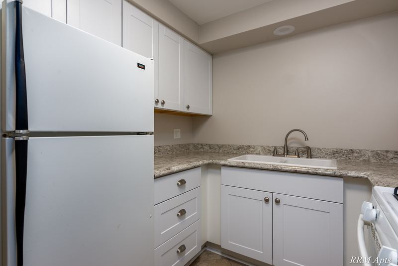 Kitchen with white cabinets, white refrigerator, sink and granite-look counter, Slusser Street apartment 7