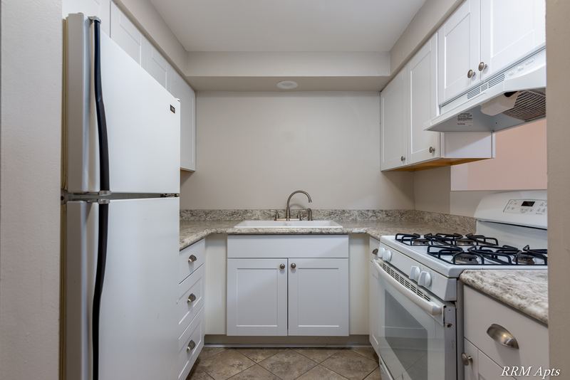 Kitchen with white cabinets, white refrigerator and gas stove, and granite-look counters, Slusser Street apartment 7