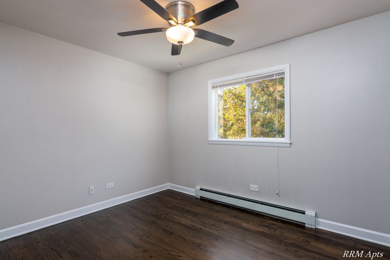 Empty room with dark wood floor, ceiling fan, one window and a baseboard heater, Slusser Street apartment 7