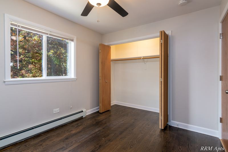 Bedroom with dark wood floor, window with trees outside, ceiling fan and bifold-door closet, Slusser Street apartment 7
