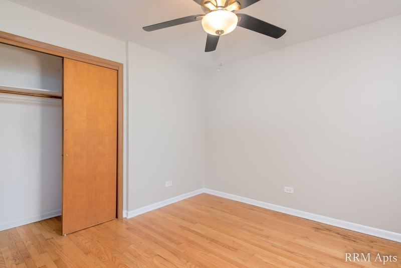 Bedroom with wood floor, ceiling fan, open wood sliding-door closet and baseboard radiator, Slusser Street apartment 8