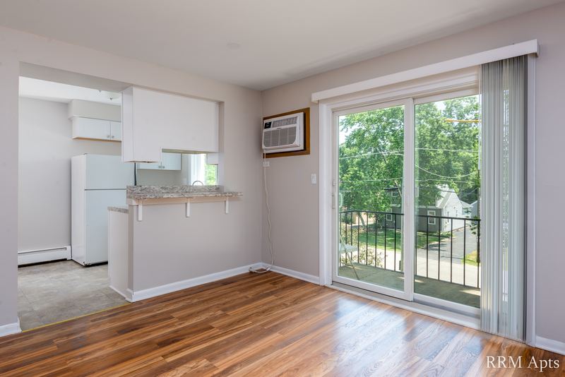 Living room with wood floor, kitchen pass-through, wall air conditioner and sliding glass door, Slusser Street apartment 8