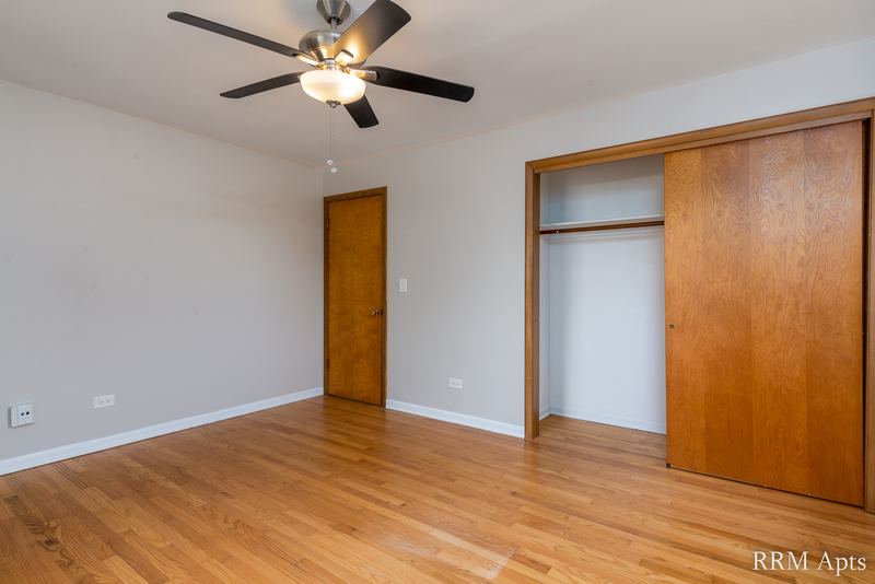 Bedroom with wood floor, ceiling fan, wood sliding-door closet and wood entry door, Slusser Street apartment 8