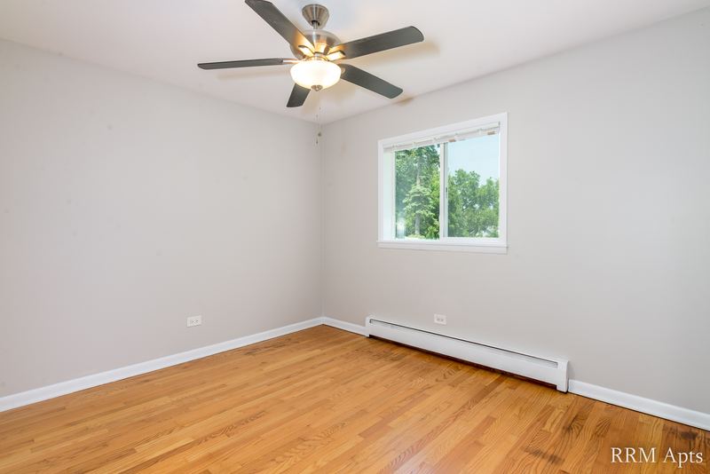 Bedroom with wood floor, ceiling fan, single window and baseboard radiator, Slusser Street apartment 8