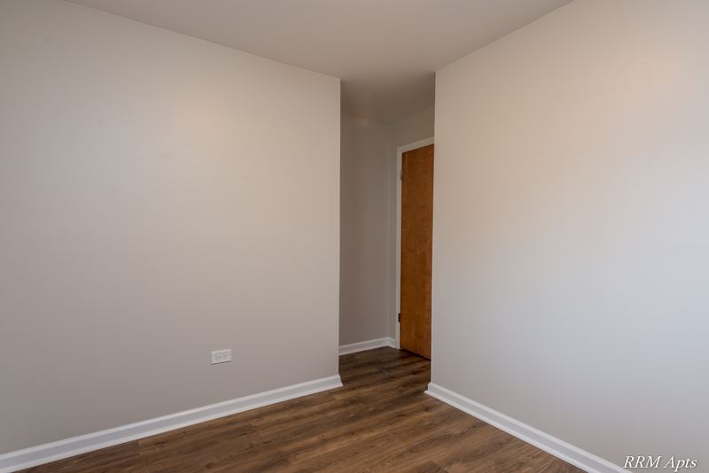 Empty room with wood floor, gray walls and doorway to the hall with a wood door, Slusser Street apartment 9