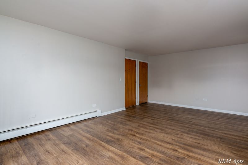 Living room with wood floor, two wood doors and baseboard radiator, Slusser Street apartment 9