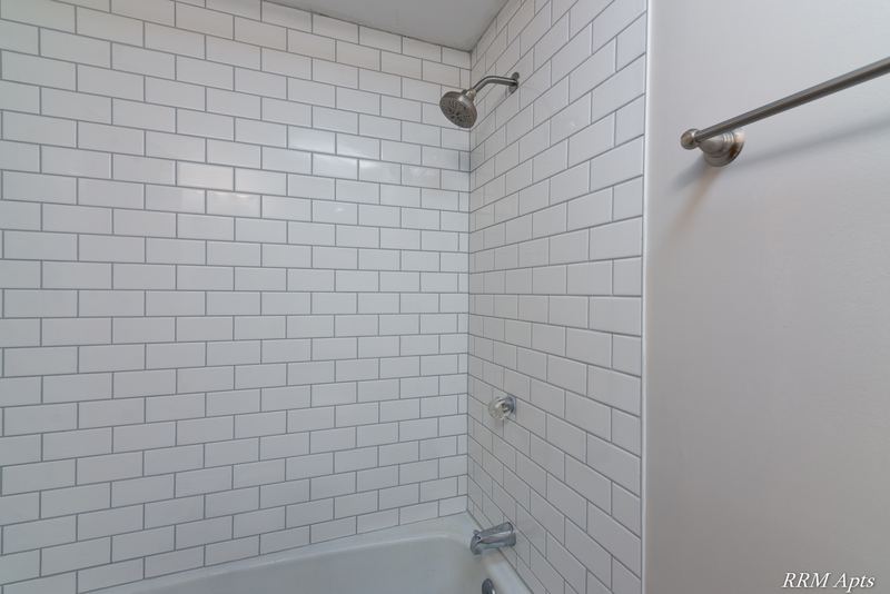 Bathroom with white subway tile tub surround, shower head and towel bar, Slusser Street apartment 9