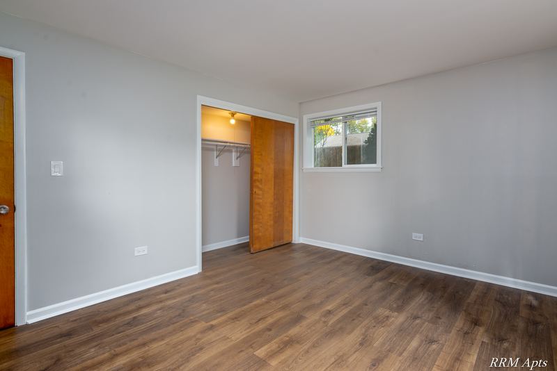 Bedroom with wood floor, open closet, wood entry door and window, Slusser Street apartment 9