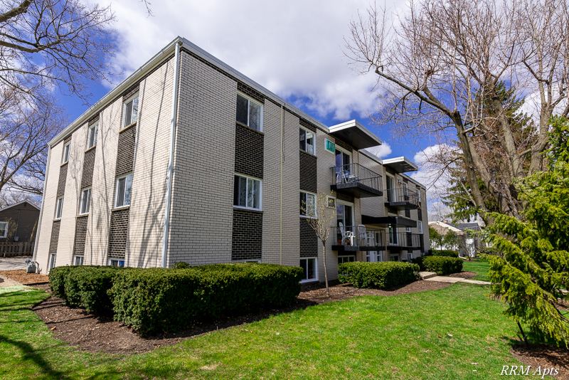 Three-story brick apartment building with balconies and lawn at Slusser Street, Grayslake