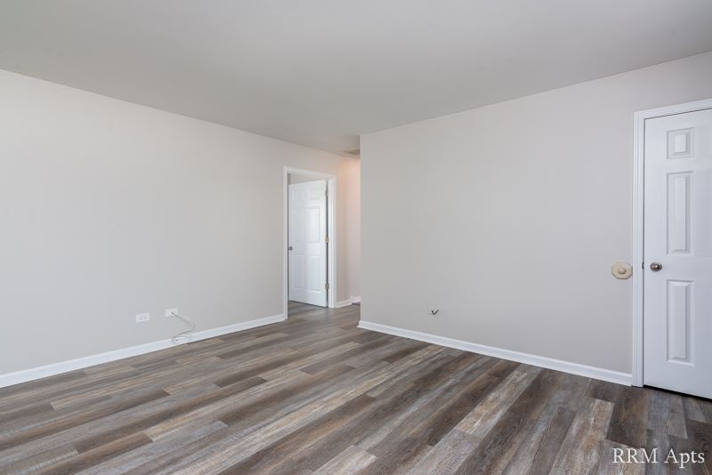 Empty living area with gray wood-look floor and doorway to the hall, South Slusser apartment 4