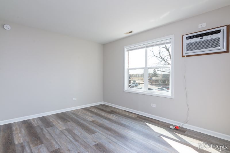 Bedroom with two windows, wall air conditioner and gray wood-look floor, South Slusser apartment 4