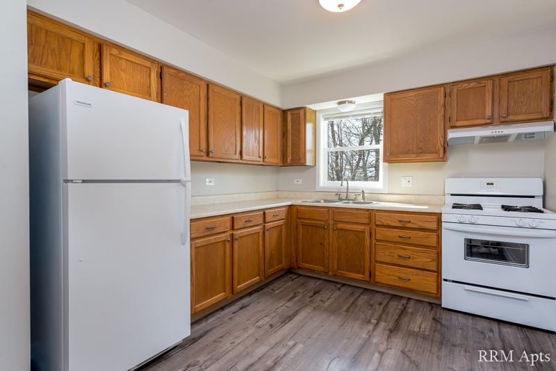 Kitchen with oak cabinets, white refrigerator, gas stove and window over the sink, South Slusser apartment 4