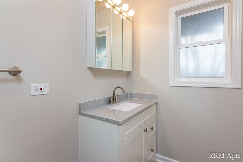 Bathroom vanity with gray countertop, mirrored medicine cabinet and frosted window, South Slusser apartment 4