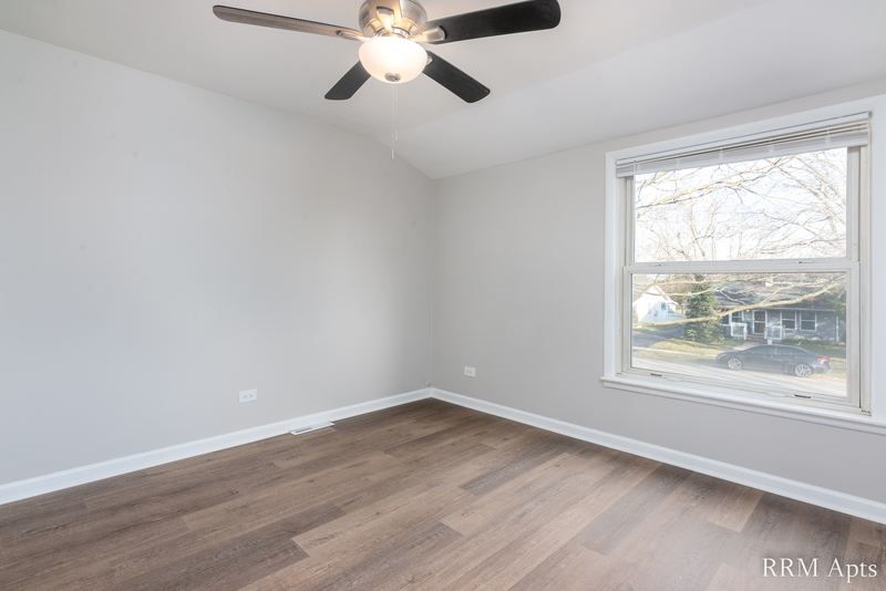 Bedroom with wood floor, ceiling fan and single window facing trees, South Slusser apartment 430