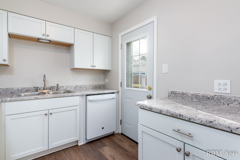 Kitchen with white cabinets, white dishwasher, granite-look counter and glass-paned door, South Slusser apartment 430