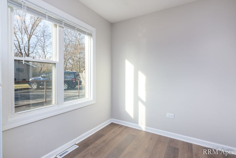 Empty room with wood floor, wide window facing the street and sunlight on the walls, South Slusser apartment 430