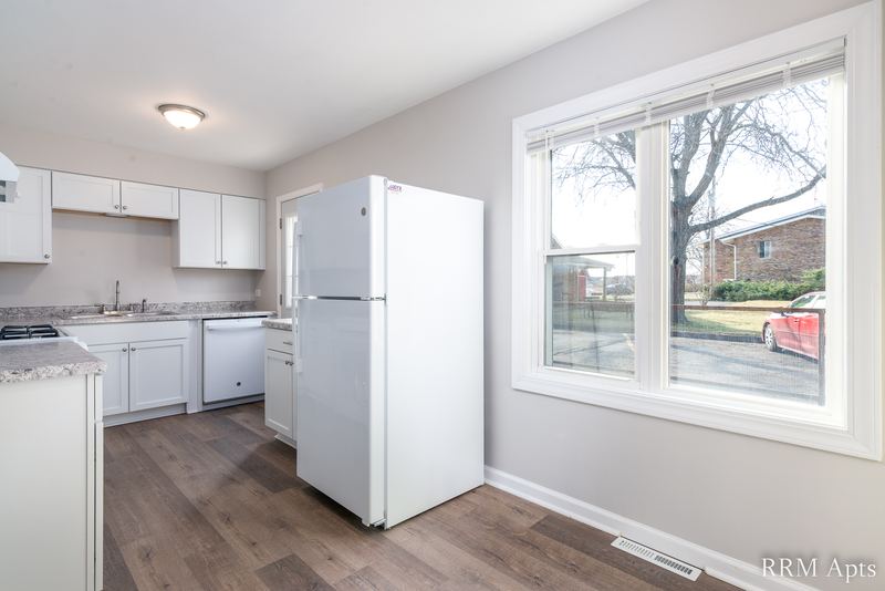 Kitchen with white cabinets, white refrigerator, dishwasher and wide window facing the street, South Slusser apartment 430