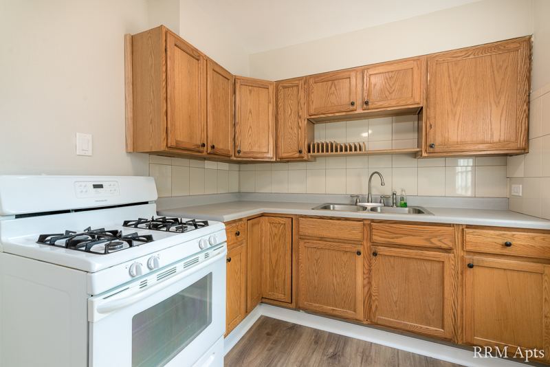 Kitchen with oak cabinets, white gas stove and tile backsplash, South Slusser apartment 434