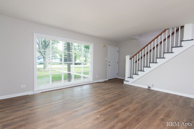 Living room with a large picture window, front door and staircase to the second floor, South Slusser apartment 434