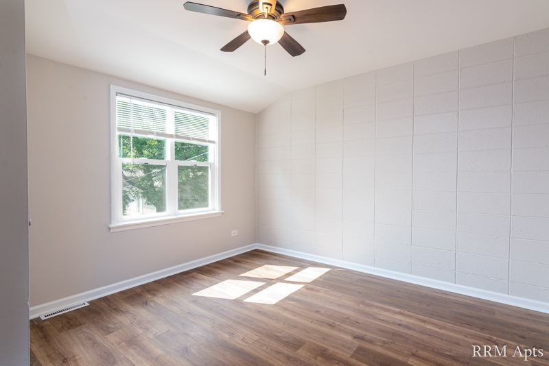 Bedroom with ceiling fan, window and wood-look floor, South Slusser apartment 434