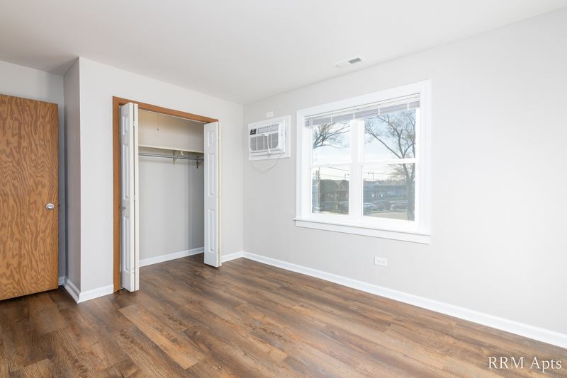 Bedroom with laminate floor, open closet, wall air conditioner, window and wood door, South Slusser apartment 440-5