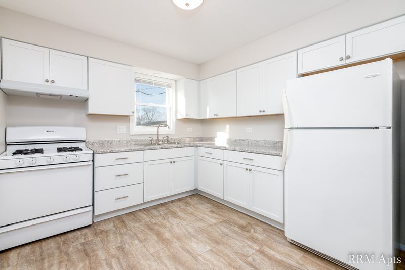 Kitchen with white cabinets, white gas stove, white refrigerator and window over the sink, South Slusser apartment 440-5