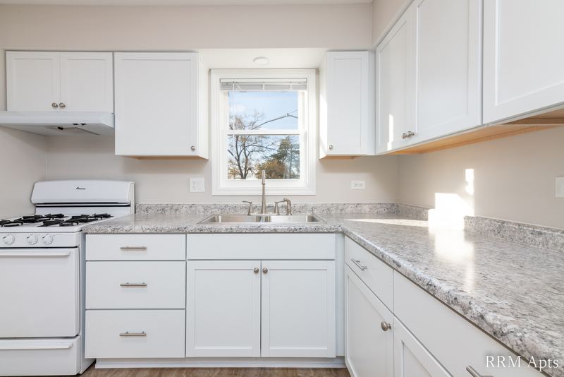 Kitchen with white cabinets, white gas stove, granite-look counter and window over the sink, South Slusser apartment 440-5