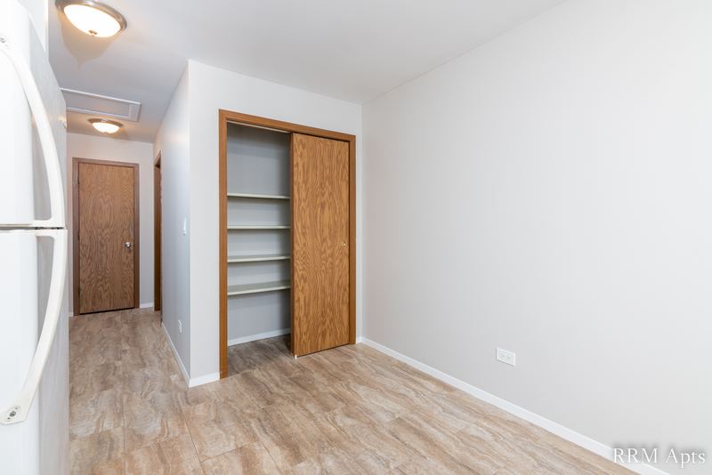 Hallway with laminate floor, white refrigerator, wood-shelved closet and wood door, South Slusser apartment 440-5