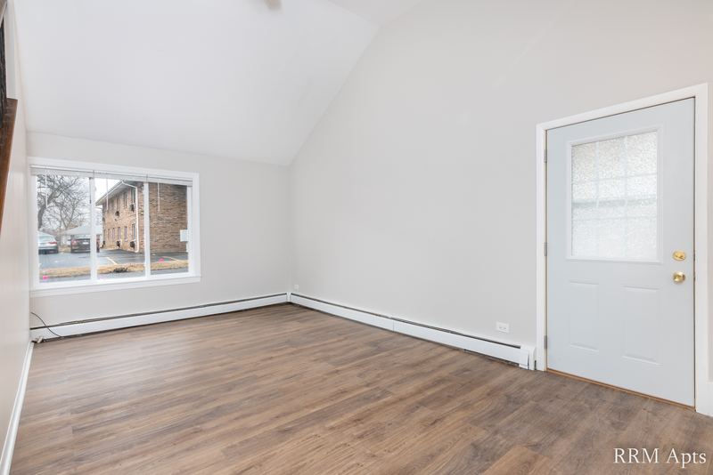 Living room with wood floor, vaulted ceiling, window and glass-paned white door, South Slusser apartment 51 St Paul