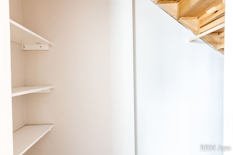 Closet with white shelves and exposed wood rafters overhead, South Slusser apartment 51 St Paul