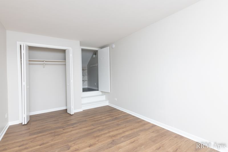 Bedroom with wood floor, open closet with hanging rod and window, South Slusser apartment 51 St Paul