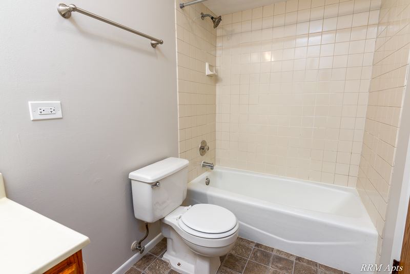 Bathroom with white tile tub surround, white toilet, towel bar and vanity corner, South Slusser apartment 440-6