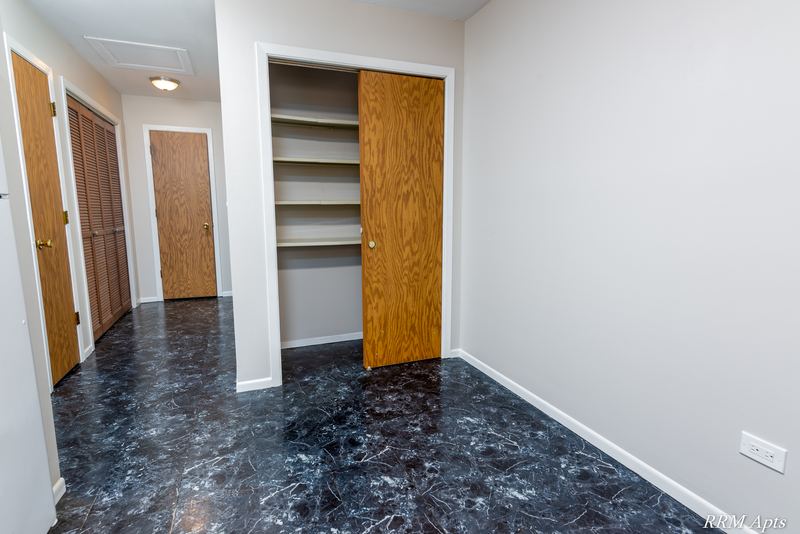 Hallway with dark marble-look floor, wood doors and wood-shelved closet with sliding door, South Slusser apartment 440-6