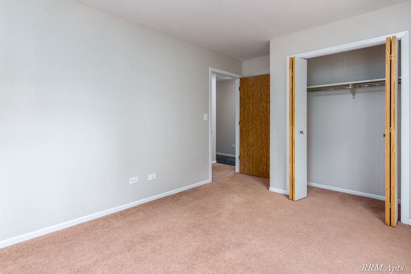Bedroom with beige carpet, open bifold-door closet and wood entry door, South Slusser apartment 440-6