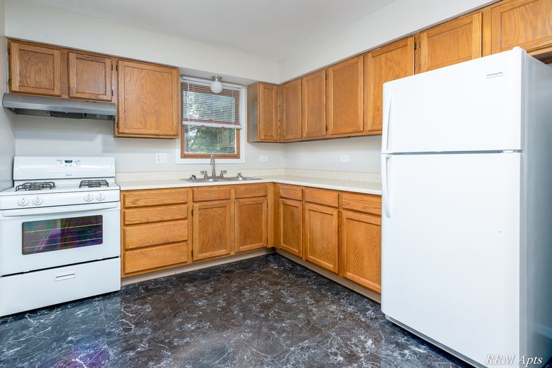Kitchen with oak cabinets, white gas stove, white refrigerator and dark marble-look floor, South Slusser apartment 440-6