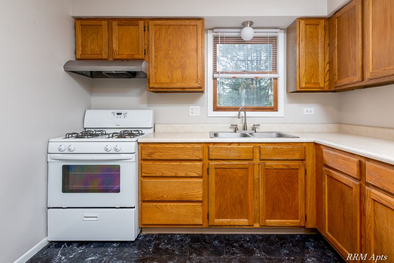 Kitchen with oak cabinets, white gas stove, range hood and window over the sink, South Slusser apartment 440-6